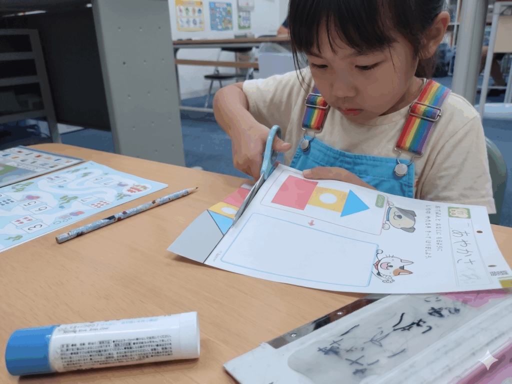 ハサミを使ってプリントに取り組む女の子。